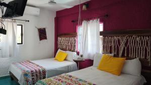 two beds in a room with red walls and yellow pillows at Hotel Gutierrez in Celestún