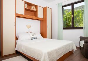 ein Schlafzimmer mit einem Bett mit weißen Laken und einem Fenster in der Unterkunft Apartment Mira in Supetarska Draga