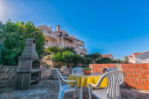 een tafel en stoelen voor een huis bij Apartments Paco in Postira