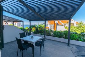 a patio with a white table and chairs on a balcony at Apartments Terrace in Postira