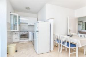 a white kitchen with a refrigerator and a table at Apartments Terrace in Postira