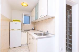 a white kitchen with a sink and a refrigerator at Apartments Terrace in Postira +64 photos