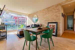 een woonkamer met een tafel en groene stoelen bij Brick apartment two blocks from plaza Rio de Janeiro Roma in Mexico-Stad