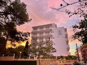 Biały budynek z zegarem na boku w obiekcie Hotel Selva Arenal w El Arenal