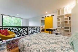 メキシコシティにあるChic Loft Near Top Dining and Architectureのベッドルーム(大型ベッド1台、黄色い椅子付)