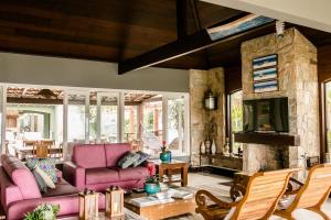 a living room with pink furniture and a stone fireplace at Casa pe na areia em Buzios in Búzios