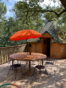 a table and chairs with an umbrella on a deck at Les cabanes de la palombière in Allons
