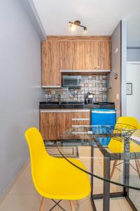 a kitchen with a glass table and yellow chairs at Alphaville-Industrial com cozinha-piscina e academia-500mega in Barueri