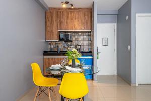 a dining room with a glass table and yellow chairs at Alphaville-Industrial com cozinha-piscina e academia-500mega in Barueri
