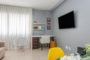 a living room with a desk and a tv on a wall at Alphaville-Industrial com cozinha-piscina e academia-500mega in Barueri