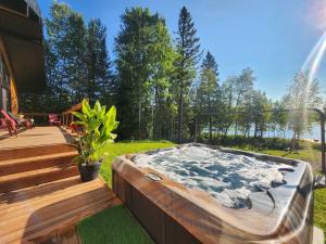 a hot tub in a backyard with a wooden deck at Chalet - Mon toit pour toi ! Bord de lac in Hébertville
