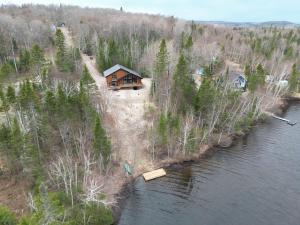 a man standing in front of a house next to a river at Cozy Chalet by the Lake - Your Perfect Escape in Hébertville