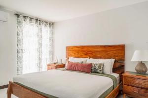 a bedroom with a bed with a wooden headboard and a window at Casa Tranquila - Ciudad del Mar 90 in Jacó +37 photos