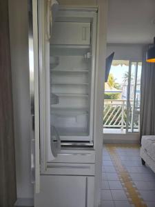 un réfrigérateur vide avec une porte ouverte dans une pièce dans l'établissement Studio bord de Mer avec Piscine - Le Manganao, Saint-François, à Saint-François 33 autres photos