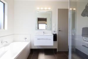 a bathroom with a tub and a sink and a mirror at 26 On Clearwater in Blenheim