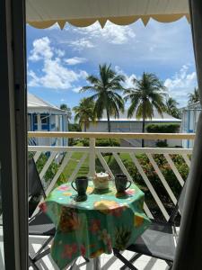 - une table avec deux tasses sur un balcon avec des palmiers dans l'établissement Studio bord de Mer avec Piscine - Le Manganao, Saint-François, à Saint-François