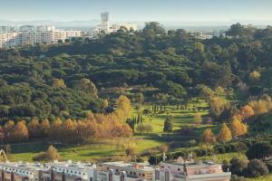 um edifício numa colina com árvores e edifícios em Mercure Lisboa Almada em Almada