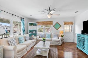 a living room with white furniture and a tv at The Marlin House 143 Marlin Drive home in Holden Beach