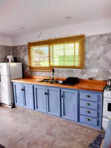 a kitchen with blue cabinets and a white refrigerator at La Casita in Embalse