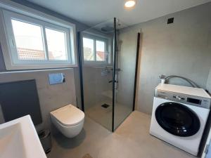 a bathroom with a toilet and a washing machine at Nostalgic Nook 27 by Stavanger BnB in Stavanger