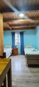 a room with two beds and a wooden ceiling at La Cima HOSTERIA in El Chalten