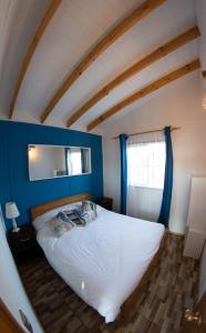 una camera con un letto bianco e una parete blu di Cabaña con Tinaja a pasos del Mar a El Quisco
