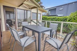 a patio with a table and chairs on a deck at 27 Kanangra Street Pambula Beach in Pambula Beach +14 photos
