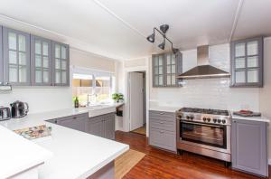 cocina con armarios grises y horno con fogones en Cowra Cottage, en Cowra