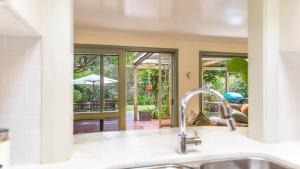 eine Küche mit einem Waschbecken und Blick auf einen Innenhof in der Unterkunft Kookaburra Cottage Pearl Beach in Pearl Beach