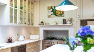 eine Küche mit weißen Schränken und einem Herd mit Backofen in der Unterkunft Kookaburra Cottage Pearl Beach in Pearl Beach + 16 Fotos