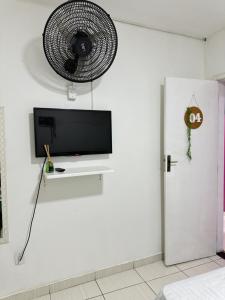 a white room with a tv and a fan on the wall at Âncora Suítes Arraial do Cabo in Arraial do Cabo