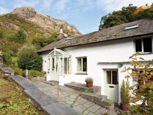 una casa blanca con una montaña al fondo en Poppy Cottage, en Coniston