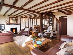 Una sala de estar con muebles de cuero y chimenea. en Poppy Cottage, en Coniston