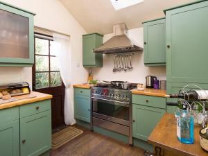 Una cocina con gabinetes verdes y una estufa. en Poppy Cottage, en Coniston
