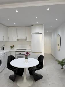 a white kitchen with a table and black chairs at Apartamento Optimist Playa de Las Americas in Playa de las Americas