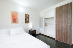 a bedroom with a white bed and a wooden door at Hotel Chalet La Sofia by Majuva in Armenia