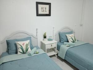 a bedroom with two blue beds and a night stand at เขายัอยวาเล่ย์ in Khao Yoi