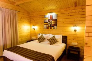 a bedroom with a bed in a wooden cabin at Tranquility Cottage Resorts in Baga