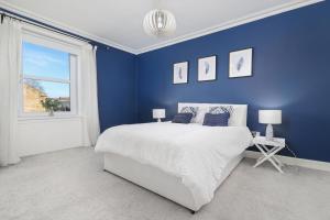 a blue bedroom with a large bed and a window at Extravagant 6 Bed Victorian Townhouse with Hot Tub in Glasgow