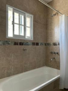 a bathroom with a bath tub and a window at Victoria casa temporario in Santo Tomé +8 photos