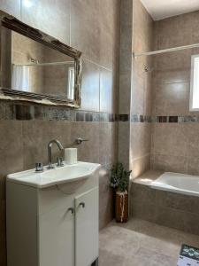 a bathroom with a sink and a tub and a mirror at Victoria casa temporario in Santo Tomé