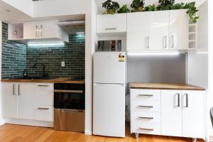 a kitchen with white cabinets and a refrigerator at Studio Loft Apartment w bikes Wifi CBD in Auckland