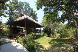 un restaurante con una cabaña de paja en un jardín en Chomjan Resort en Ko Phayam