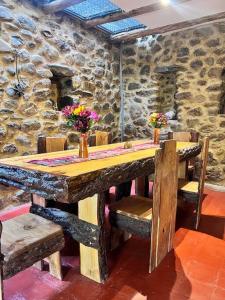 einen Holztisch mit Stühlen und eine Steinmauer in der Unterkunft Casa de piedra en Ollantaytambo in Ollantaytambo