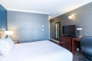 a hotel room with a bed and a desk and a television at Sandman Hotel & Suites Kelowna in Kelowna
