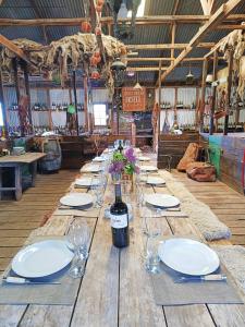 einen langen Holztisch mit Tellern und einer Flasche Wein in der Unterkunft Estancia Santa Thelma in Gobernador Gregores