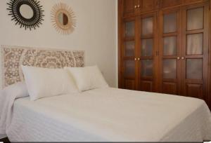 una camera da letto con un letto bianco e un armadio in legno di Casa Carmen a Nerja