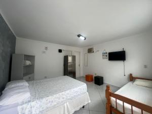a bedroom with two beds and a tv in it at Boas Vindas in Guarujá +2 photos
