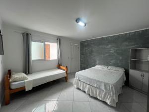 a bedroom with a bed and a large window at Boas Vindas in Guarujá