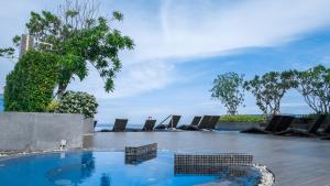 a swimming pool with lounge chairs and the ocean at Wong Amat Tower By Peter in North Pattaya